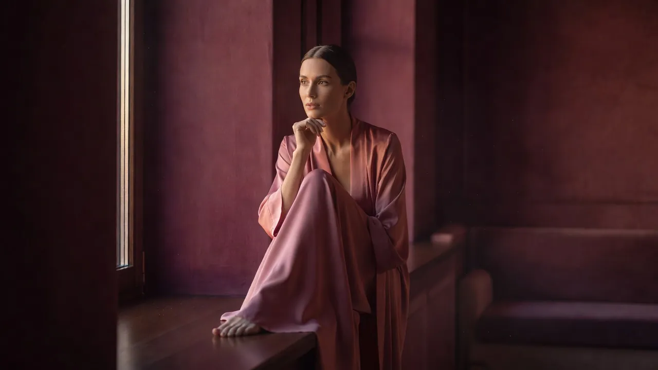 Femme en peignoir de soie à une fenêtre au petit matin